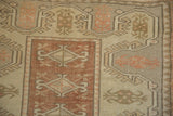 Stylized dusty copper finials and geometric motifs on a distressed vintage Melas rug.