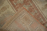 Distressed dusty copper and antique ivory Melas rug pile folded to show hand-knotted reverse and orange selvage.