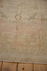 Distressed Oushak rug displaying its softened texture in antique ivory and dusty rose.