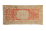 Vintage distressed Oushak runner with an ivory medallion on an abrashed raspberry red field and sea foam green borders.