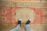 Standing perspective of a distressed Oushak runner, showing its soft raspberry red and ivory tones.