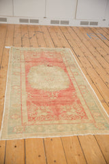 Angled view of a vintage Oushak runner with a distressed raspberry red and sea foam green palette.