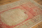 Corner detail of a distressed Oushak runner showing its scrolling floral border and low pile.