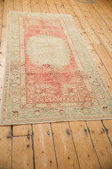 Angled view of the distressed vintage Oushak runner's raspberry red and sea foam green palette.
