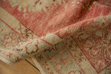 The soft, low pile and hand-knotted texture of a distressed Oushak runner in raspberry red and ivory.