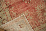 A corner of the Turkish Oushak rug folded back to show its hand-knotted construction and side selvage.