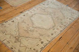 An angled view of the vintage Oushak runner shows its distressed, low pile and faded medallion design.