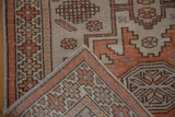 Pale burnt orange, platinum geometric patterns on distressed Oushak rug corner.