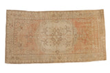 Vintage distressed Oushak rug with a central floral medallion in faded dusty rose and ivory.