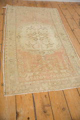 Faded floral motifs and soft abrashes of rose and ivory on a distressed vintage Oushak rug.