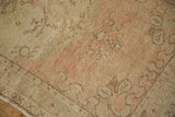 Textured corner of a vintage Oushak rug with time-softened dusty rose and beige colors.