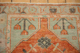 Distressed corner spandrel and serpent motif border in pale brick orange and faded mint green.