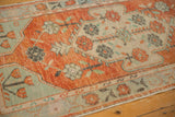 Close-up of a vintage Oushak's corner spandrel, with faded floral motifs and a distressed low pile.