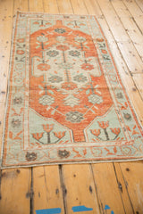 Angled view of a distressed Oushak runner in pale brick red and faded mint green.