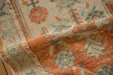 A soft fold reveals the low, hand-knotted texture of a vintage rug in brick red, ivory, and mint.