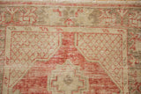 Close view of the distressed low pile showing worn knot heads in brick red and ivory geometric patterns.