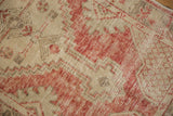 Detail of the hand-knotted pile showing wear to the brick red and ivory geometric motifs.