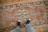Distressed Oushak runner's textured pile showing dusty red blush and ivory stepped designs.