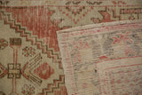 Distressed vintage Oushak rug shows worn red pile and woven back foundation details.
