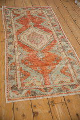 Distressed vintage Oushak rug corner with brick red, pale blue, and ivory geometric patterns.