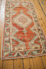 Distressed texture of the Oushak runner with brick red, pale blue, and ivory geometric patterns.