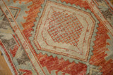 Distressed Oushak rug with faded brick red, pale blue, and ivory geometric patterns.