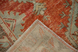 Worn brick red and pale blue distressed pile of the vintage Oushak, revealing its hand-knotted back.