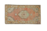 Vintage distressed Oushak rug with a central medallion in dusty rose, gold, and pale mint green.