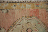 Close-up of a vintage Oushak's unique zig-zag border and soft, abrashed dusty rose pile.