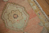 Vintage Oushak rug detail with a pale mint green floral medallion on a dusty rose field.