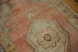 Angled close-up of the worn pile and abrashed tones on a vintage distressed Oushak rug.