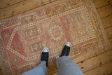 Distressed Oushak rug showing faded pink, pale red, ivory geometric starbursts and soft pile.