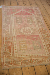 Geometric meandering vine border and starburst florals on a distressed vintage Oushak rug, showing heavy abrashes.