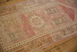 Distressed Oushak rug pile with heavy abrash, showing geometric patterns in muted pink and ivory.