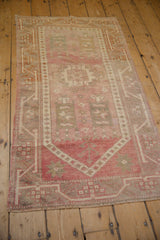 Fringed end, geometric meandering vine border, and heavy abrashes on vintage Oushak rug.
