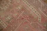 Distressed Oushak rug corner revealing low pile, geometric pattern, and reverse woven foundation.