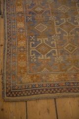 Distressed Anatolian rug corner, with blue, gold, checkered and floral borders showing wear.