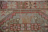 Close-up of the distressed geometric border and arrowed plant motifs on a vintage Oushak rug.
