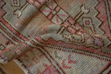 Distressed vintage Oushak rug pile, featuring geometric motifs in aubergine and silver.