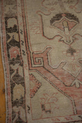 Distressed Oushak rug side: serpent motif border and textured pile in blush, beige, and brown.