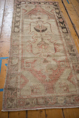 Distressed Oushak rug runner pile, showing blush red floral patterns and surface wear.