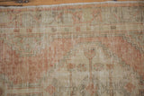 Detailed texture of a distressed Oushak rug showing worn pile and knot heads in soft rust.