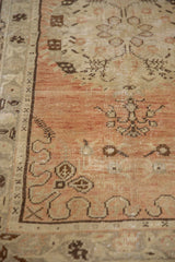 Distressed Oushak rug detail: dusty terracotta field, worn knot heads, and stylized brown patterns.