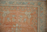Distressed vintage Oushak rug corner with pale tangerine and ocean green meandering vines.