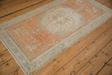 Oushak rug corner highlighting distressed texture and meandering green-blue vines.