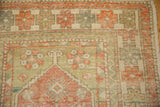 Corner detail of a distressed Oushak rug with a barber pole border and tangerine floral motifs.