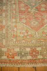 Corner view of the distressed Oushak rug's geometric and barber pole borders.