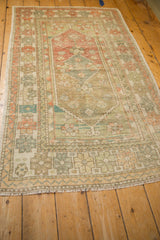 Angled perspective of a distressed Turkish Oushak rug, showing its faded medallion and sage field.