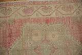 Meandering vine and blossom border in faded magenta and ivory on a distressed vintage Oushak rug.