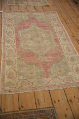 Angled view of a vintage distressed Oushak rug with a soft, faded magenta patina.